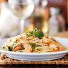 High Quality Organics Express Red Chili Pepper Crushed over shrimp pasta with wine in background